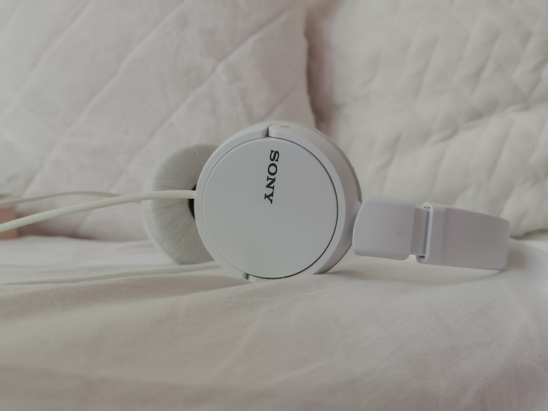 White Sony headphones on a white background by Endless Relaxation a pair of headphones sitting on top of a bed